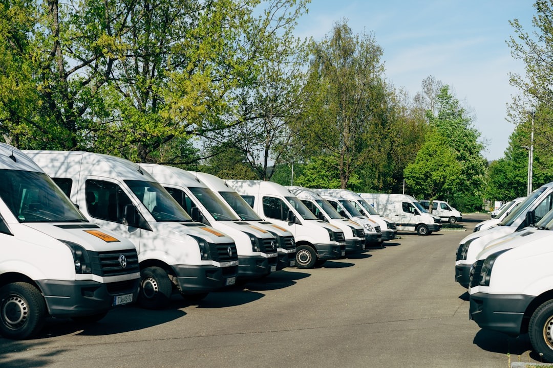 Many white delivery vans parked in a lot.